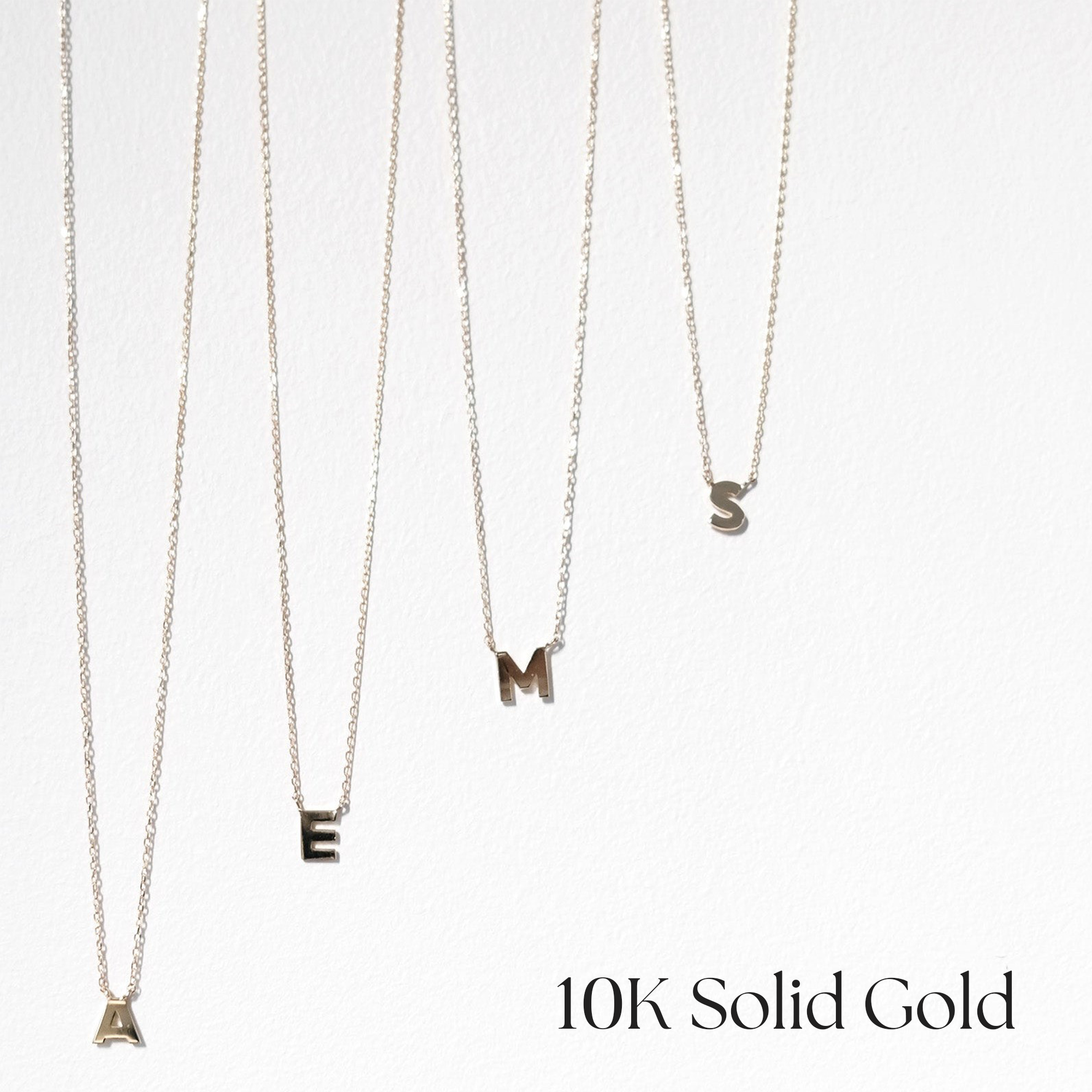 10K solid gold initial necklaces in assorted letters arranged neatly on white background