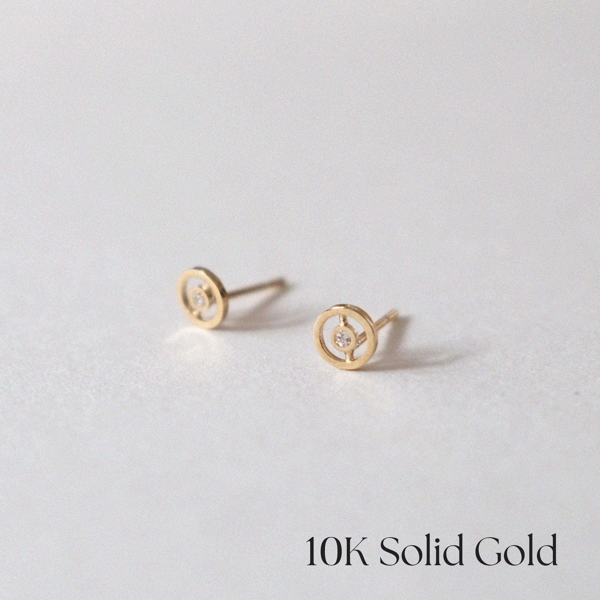 Angled view of circular gold earrings highlighting their shine and design