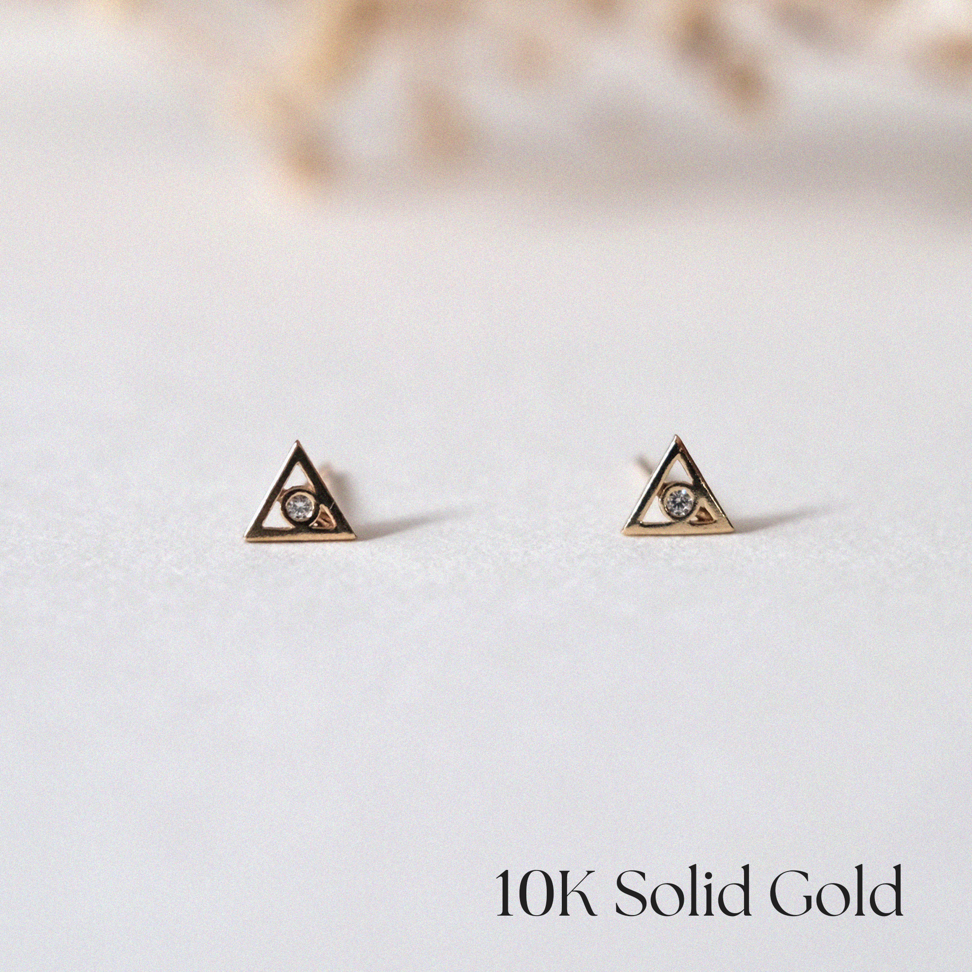 Front view of Bishop Triangle Studs with CZ center in gold triangle setting