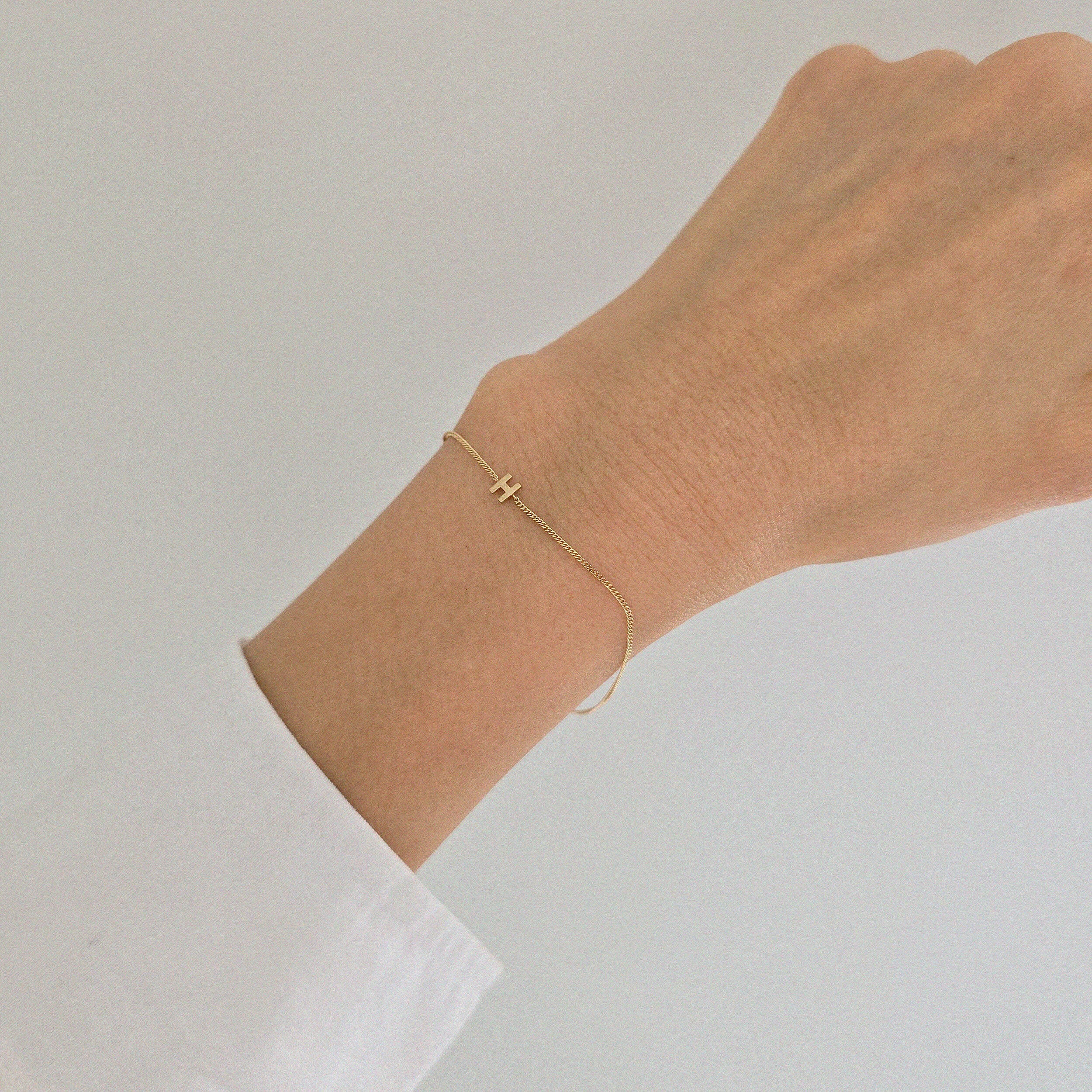 Delicate gold bracelet with personalized letter accent on wrist