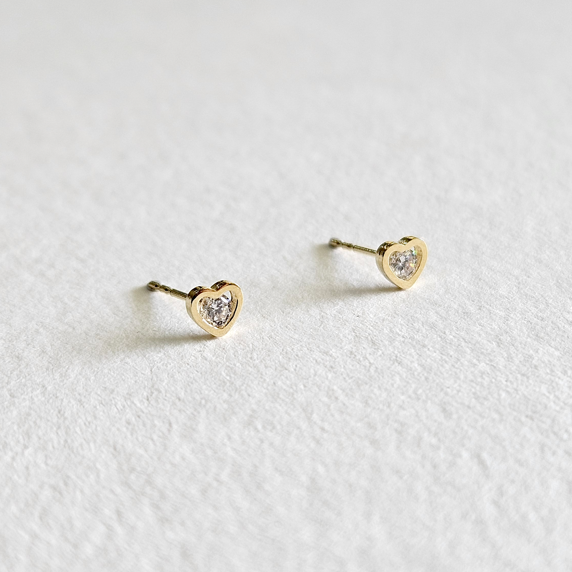 Side profile of gold heart earrings showing raised cubic zirconia