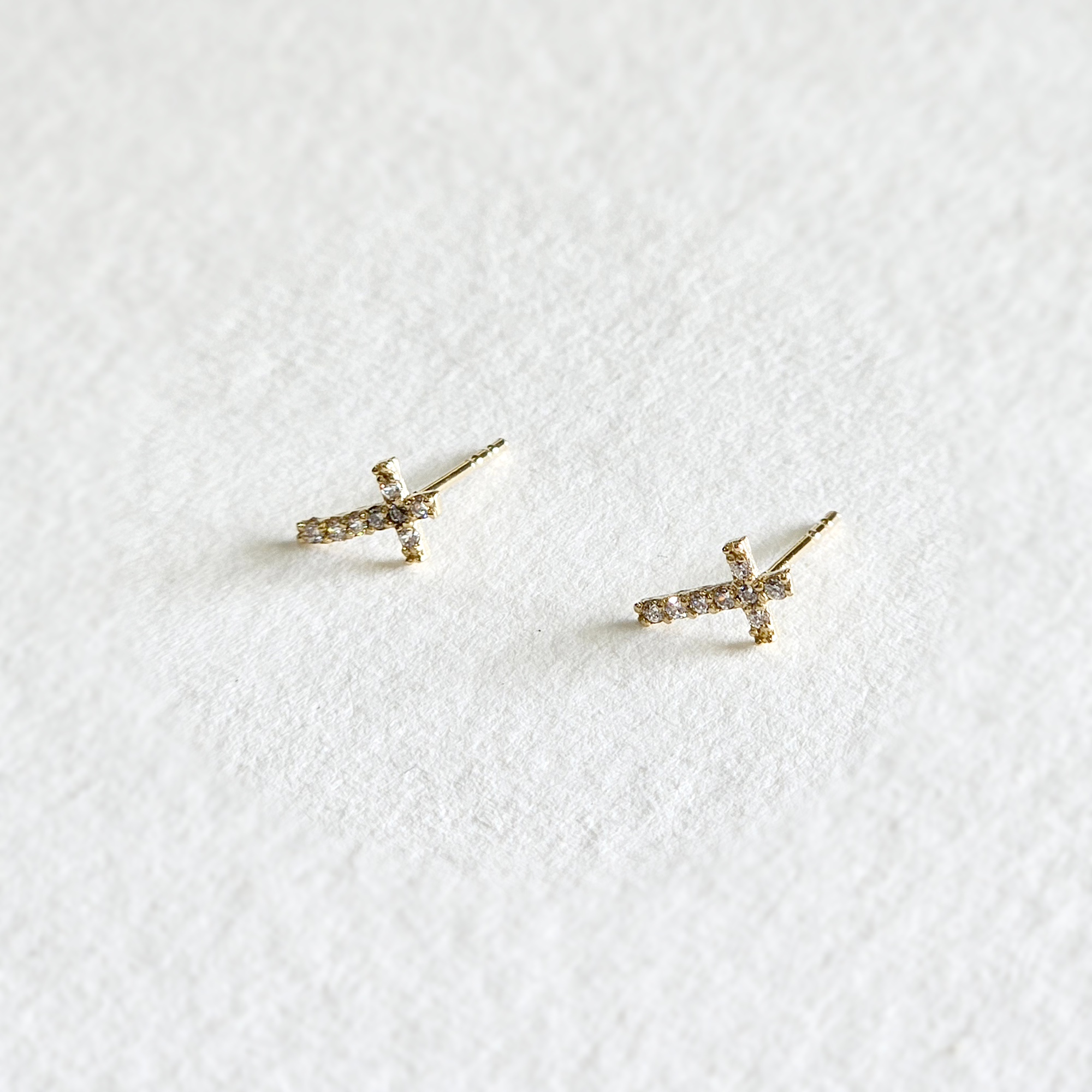 Side angle of gold cross earrings showing raised stone setting