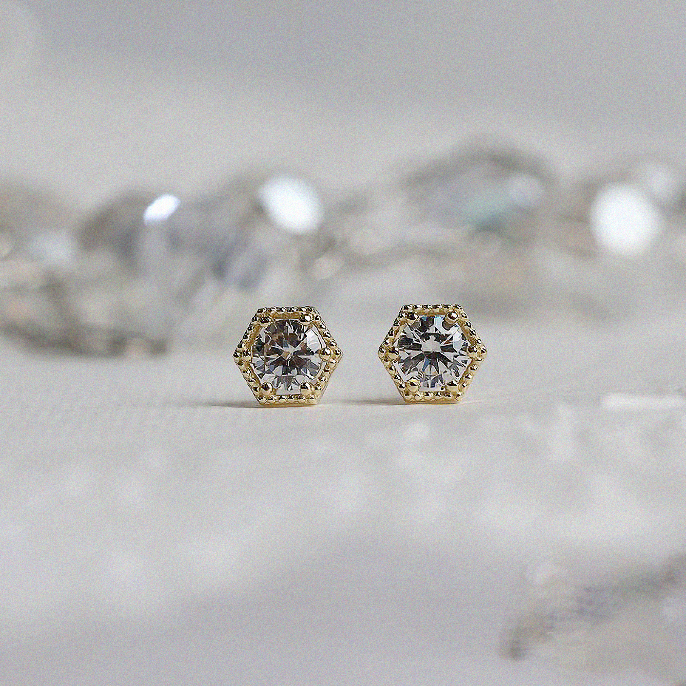 Gold hexagon-shaped studs featuring cubic zirconia sparkle
