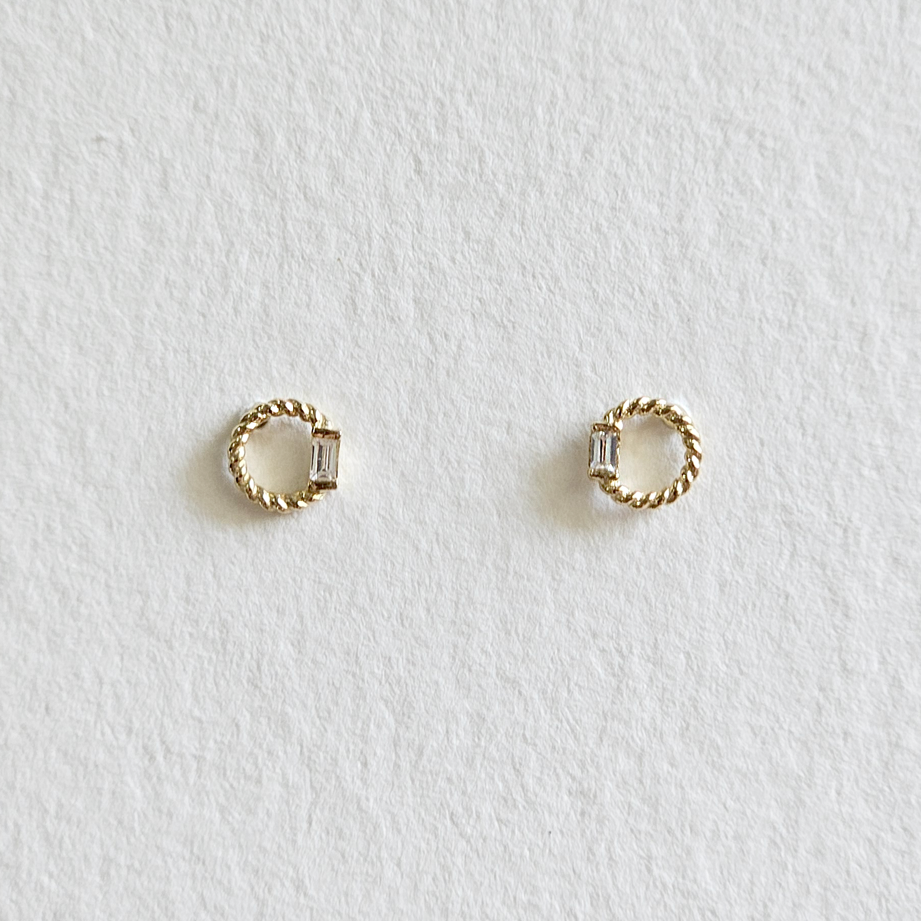 Circular gold earrings with cut cubic zirconia in center