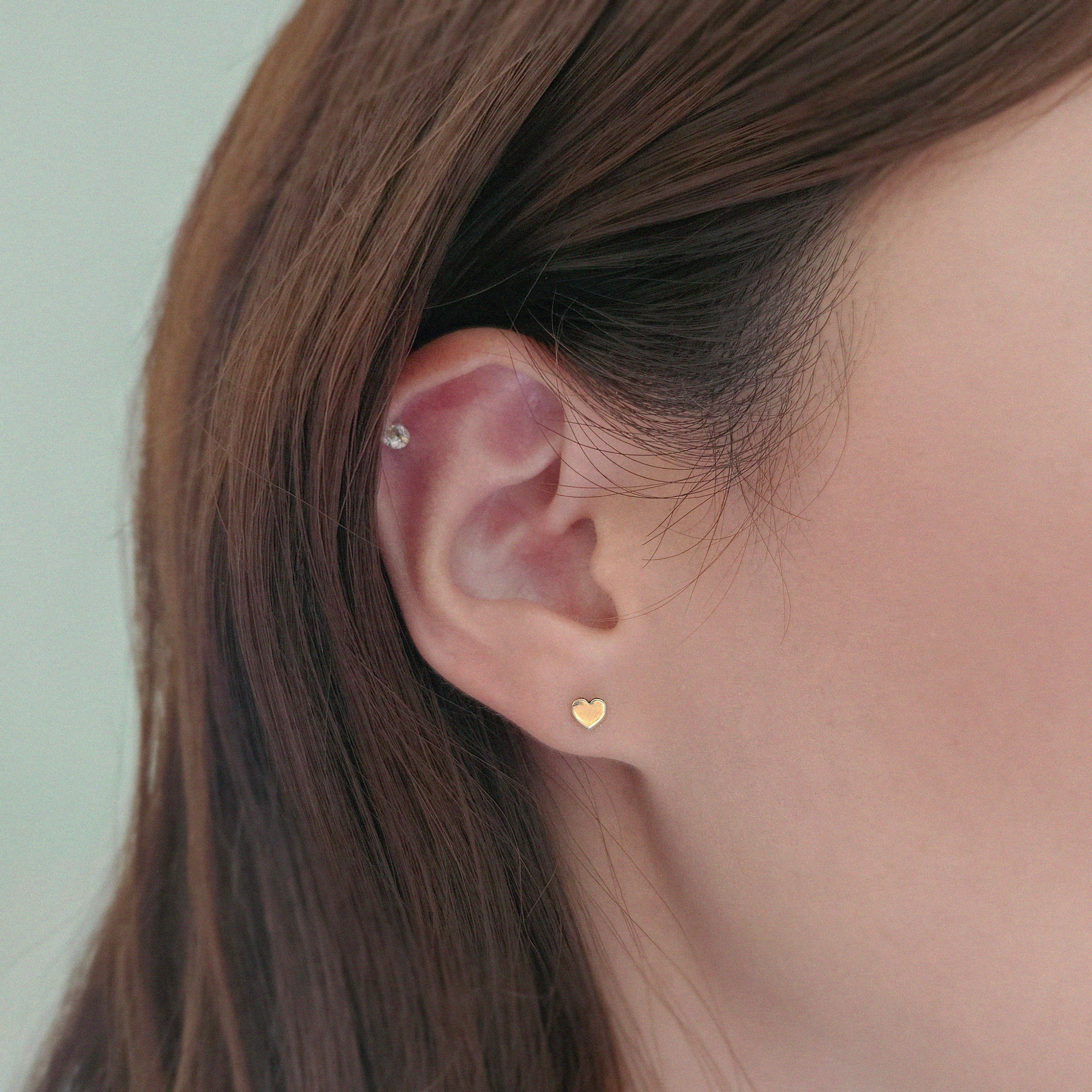 Close-up of 14K gold heart studs on ear for daily wear