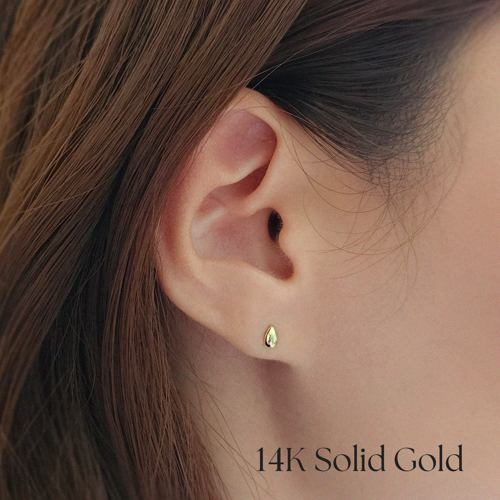 Gold teardrop earrings styled alone on earlobe