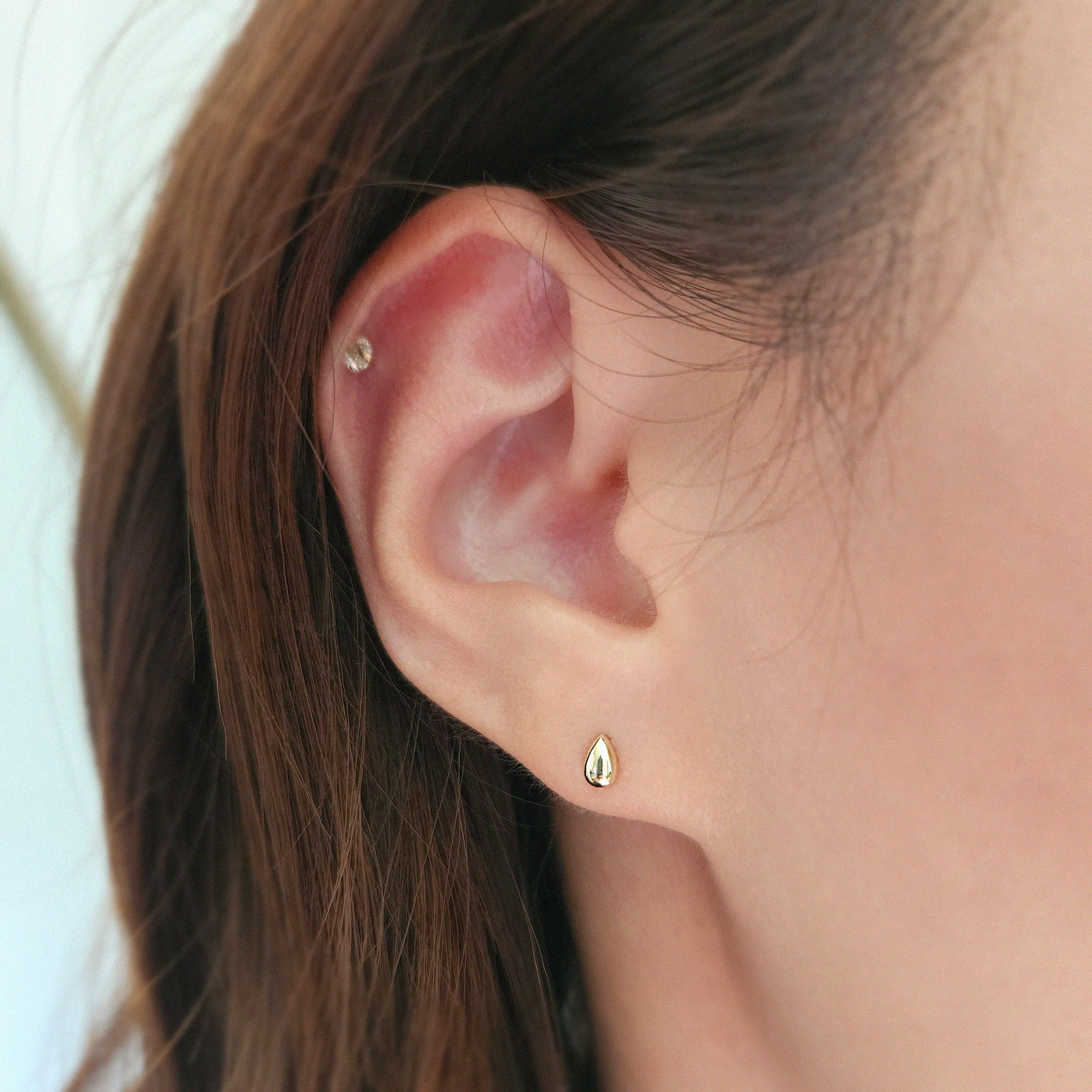 Close-up of minimalist gold earrings on model for daily wear