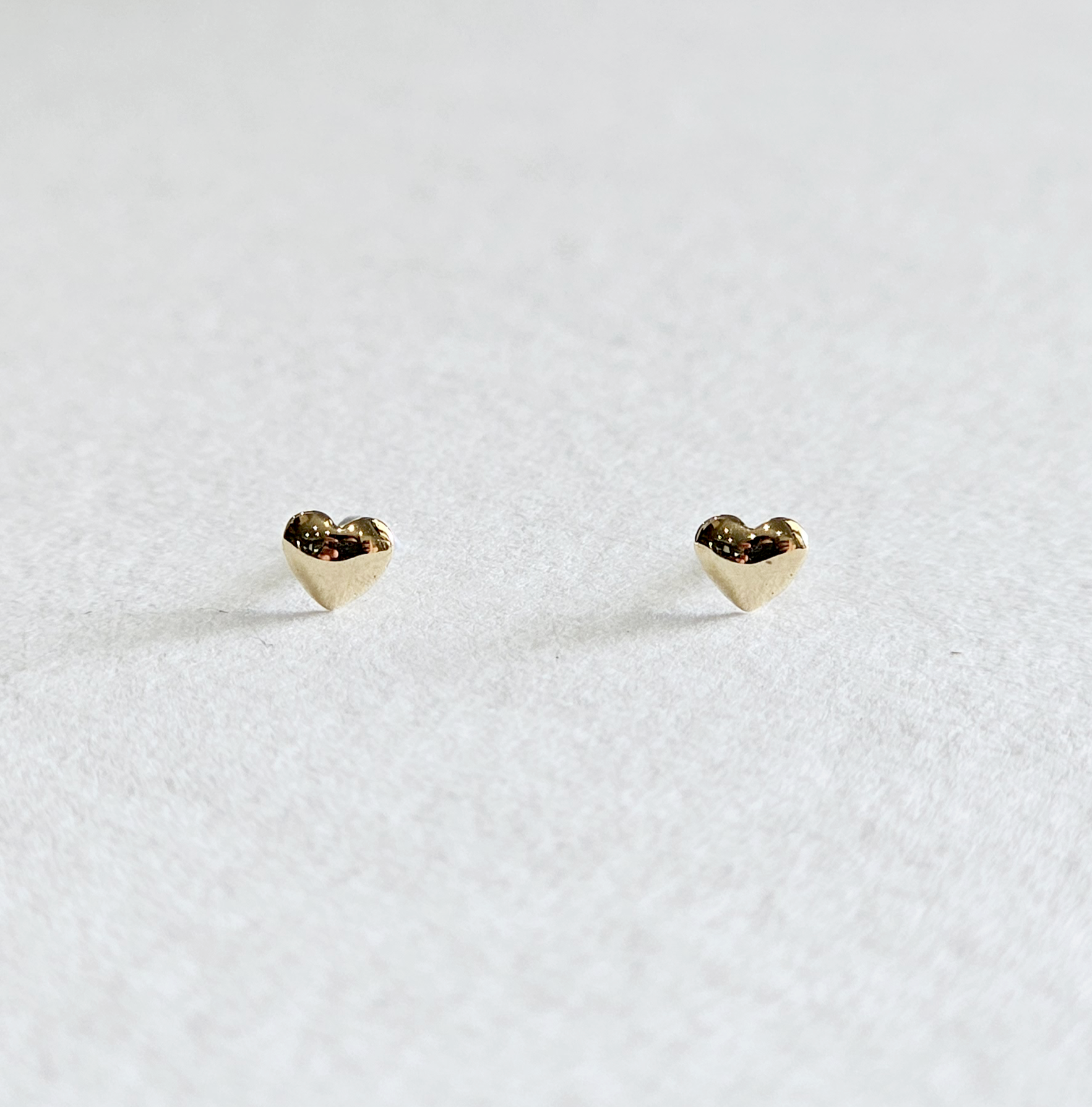 Soft 3D heart gold studs photographed from the front