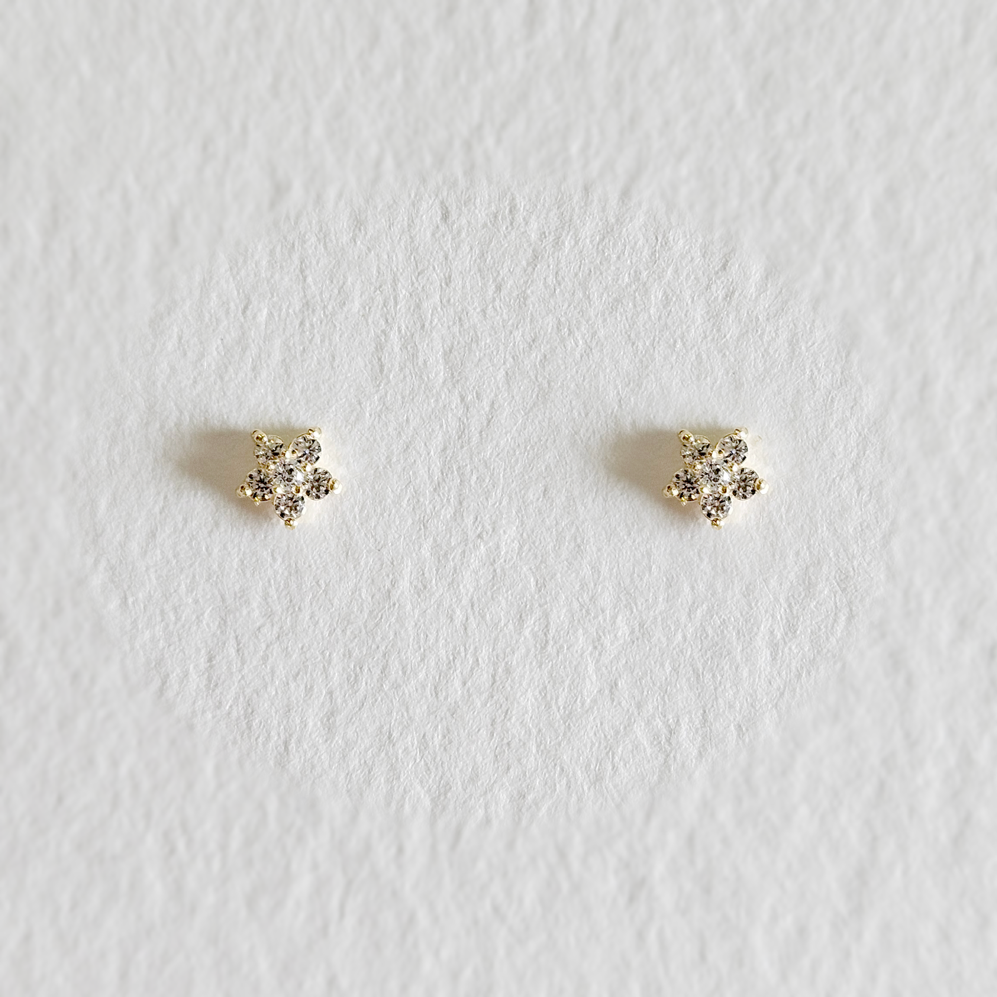 Delicate flower-shaped stud earrings featuring central cubic zirconia