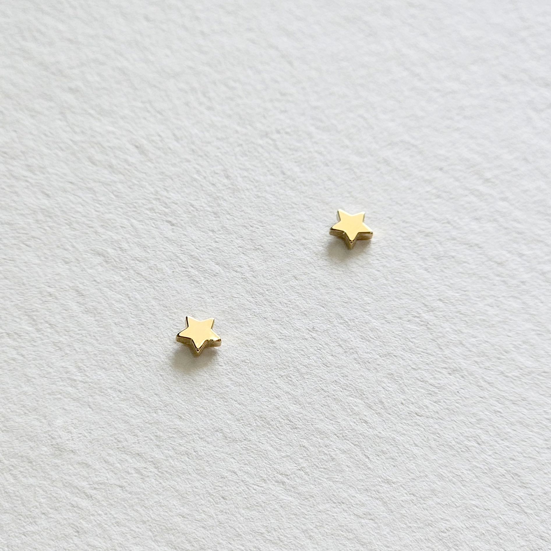 Flat lay of gold star earrings showing shine and shape