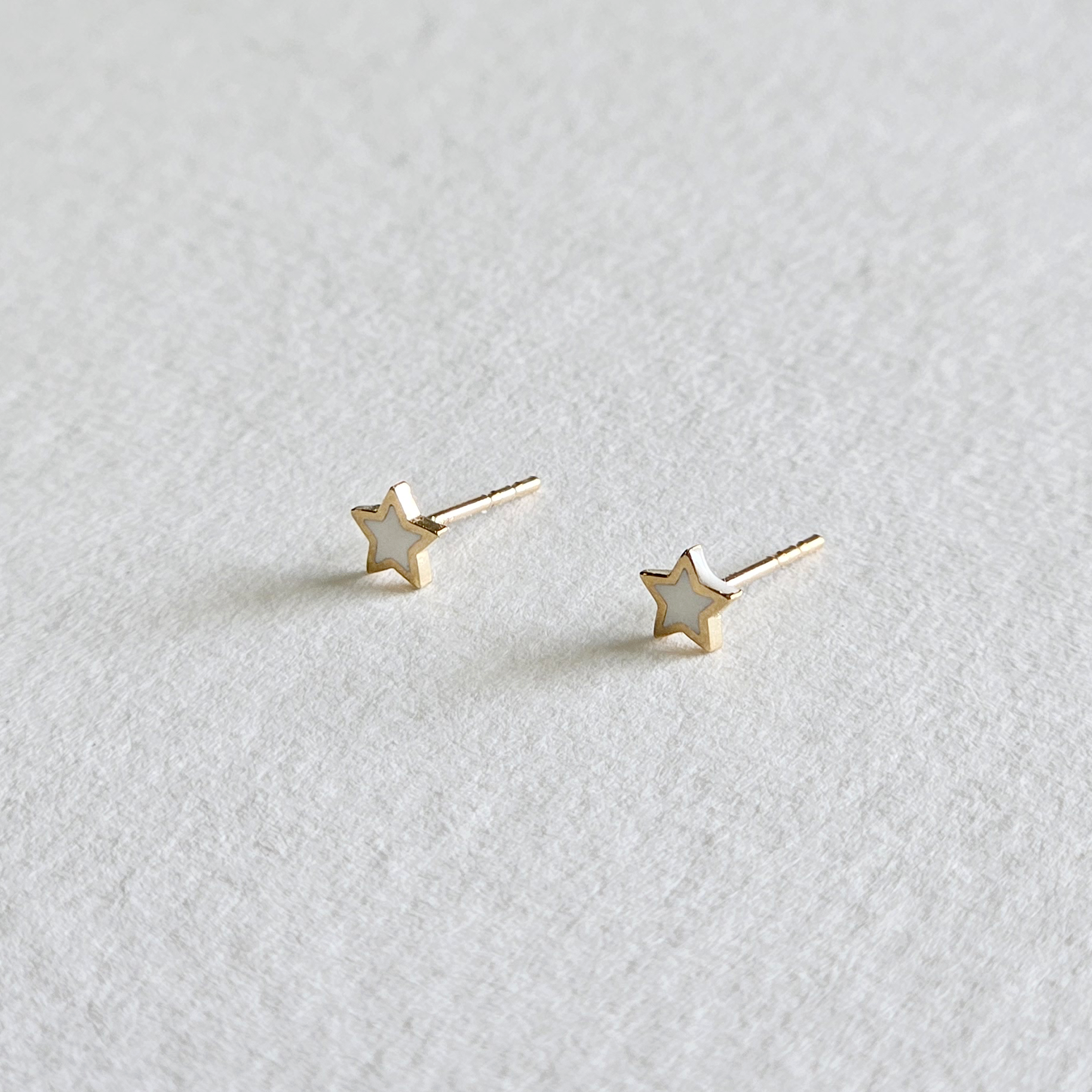 Side angle of star-shaped 14K gold earrings highlighting texture