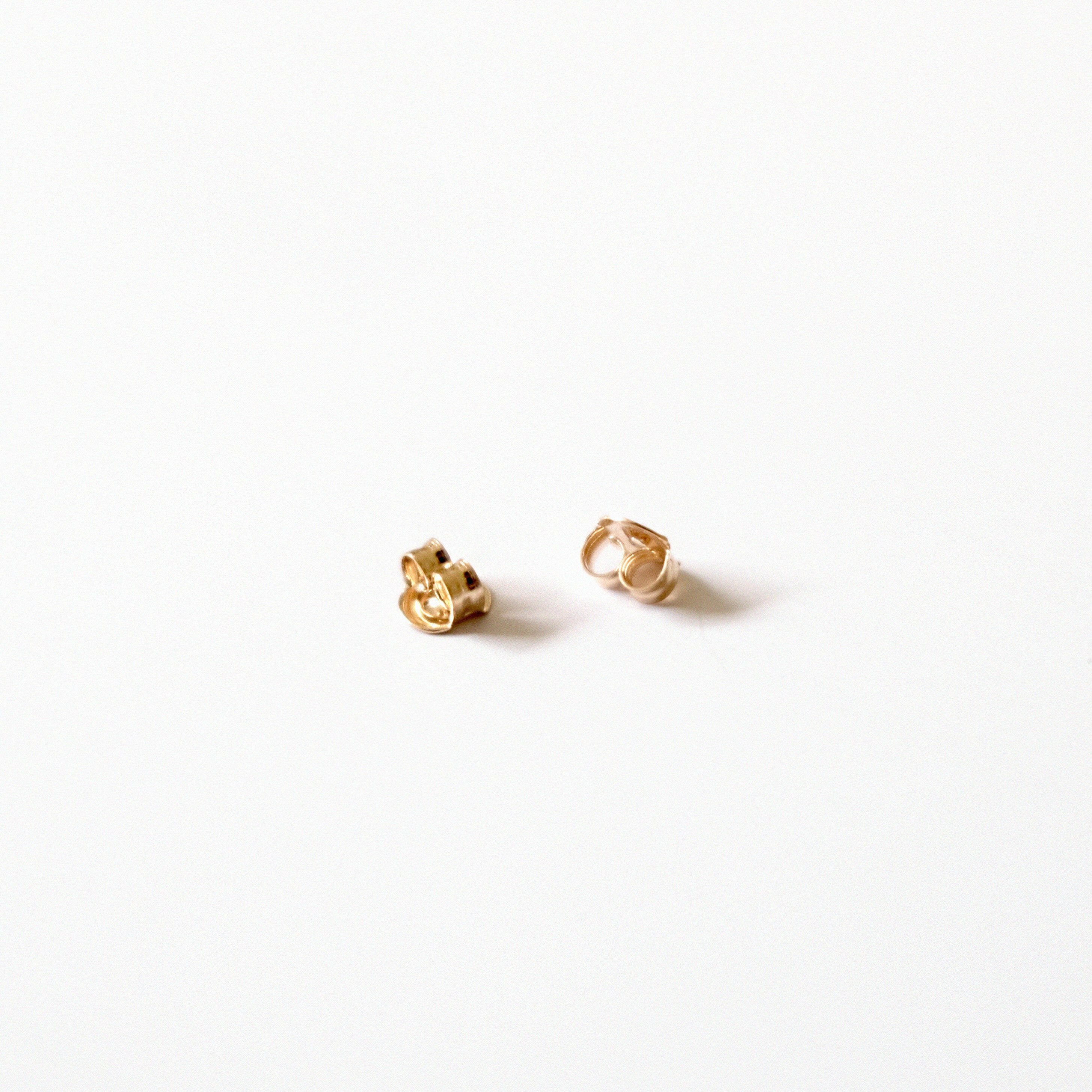 Detailed shot of 14K gold earring backs with high-shine finish and secure grip