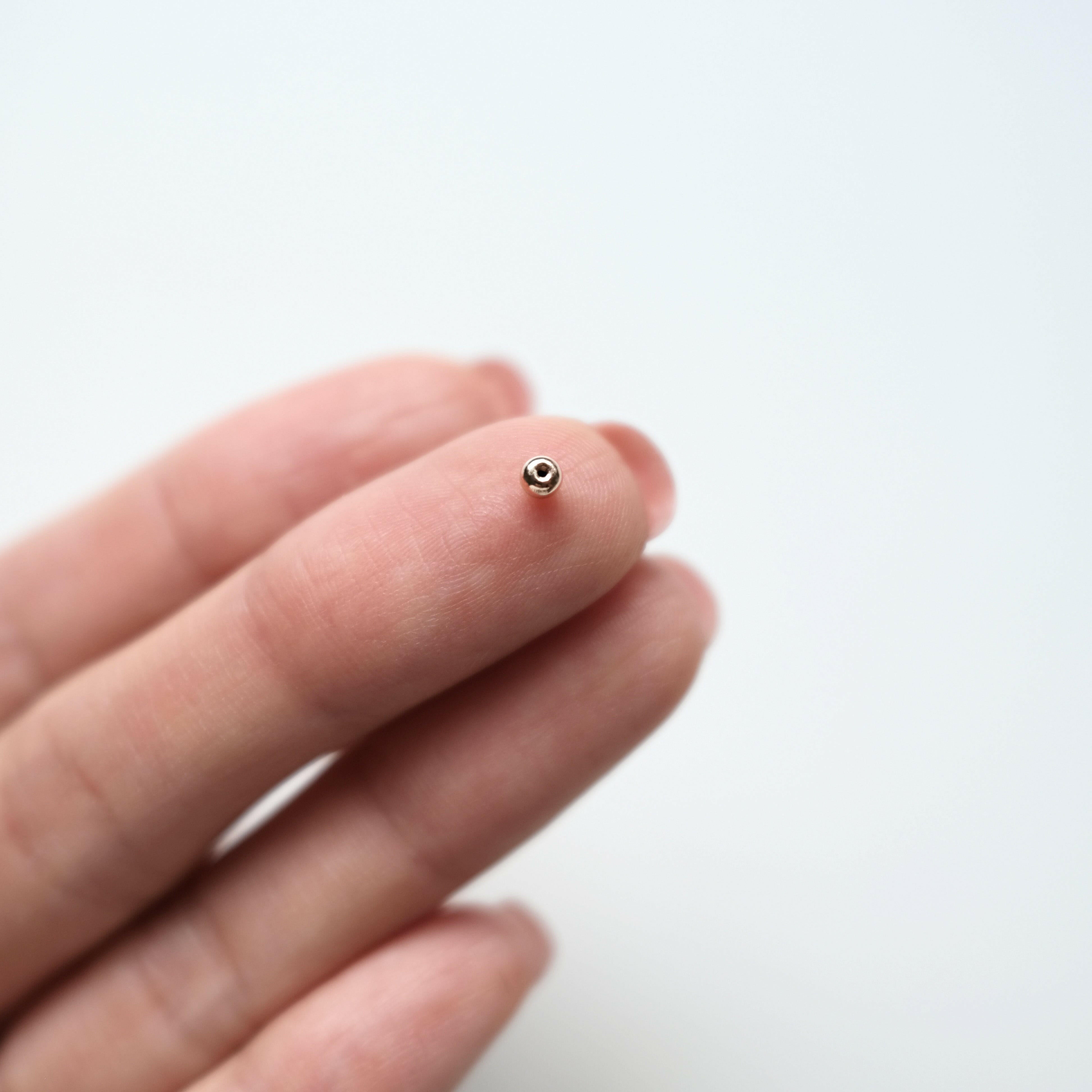 Flat lay of 2.9mm screwball earring backs and a 0.6mm post for cartilage piercings, highlighting compatibility