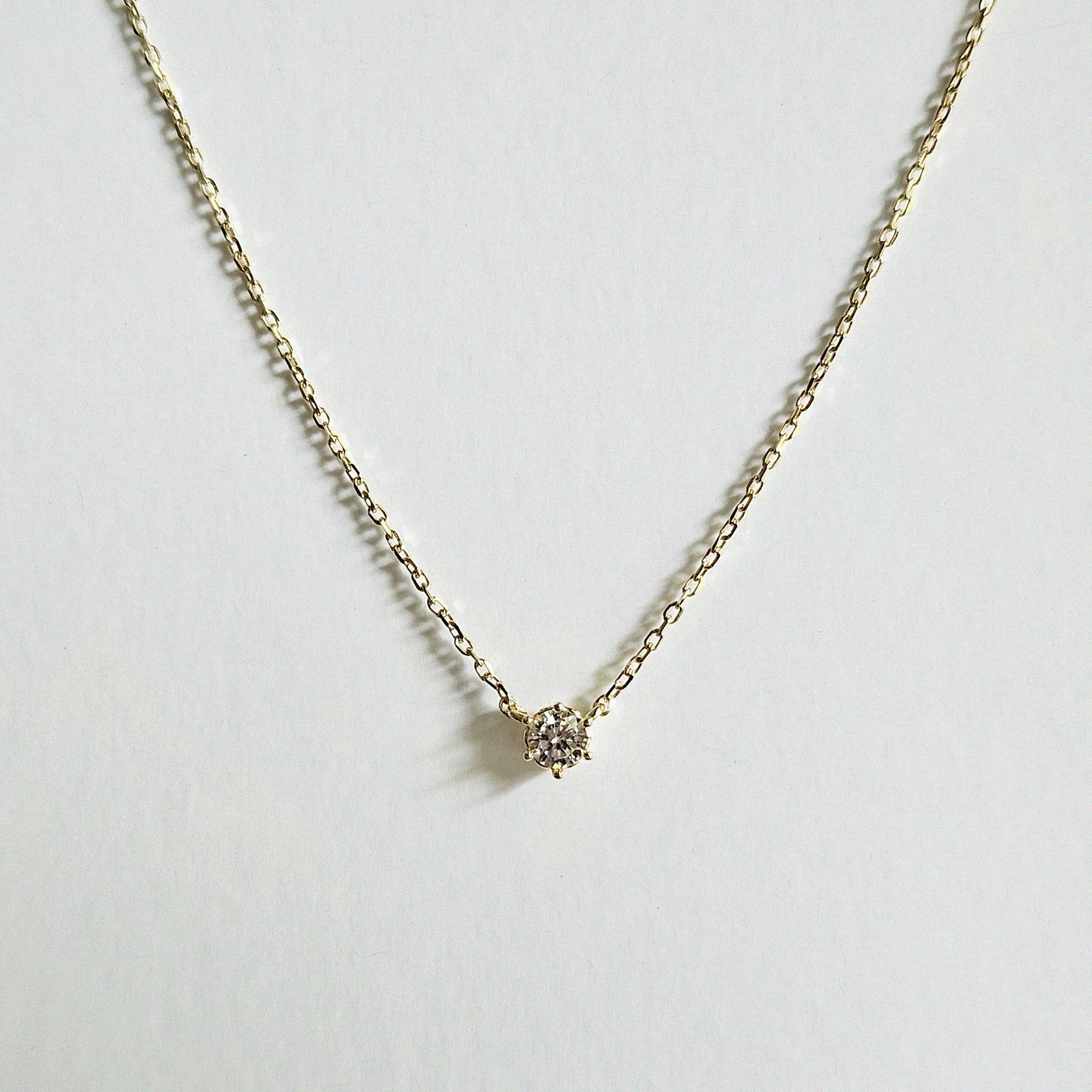 Close-up of petite CZ pendant set in high-polish 14K gold bezel setting