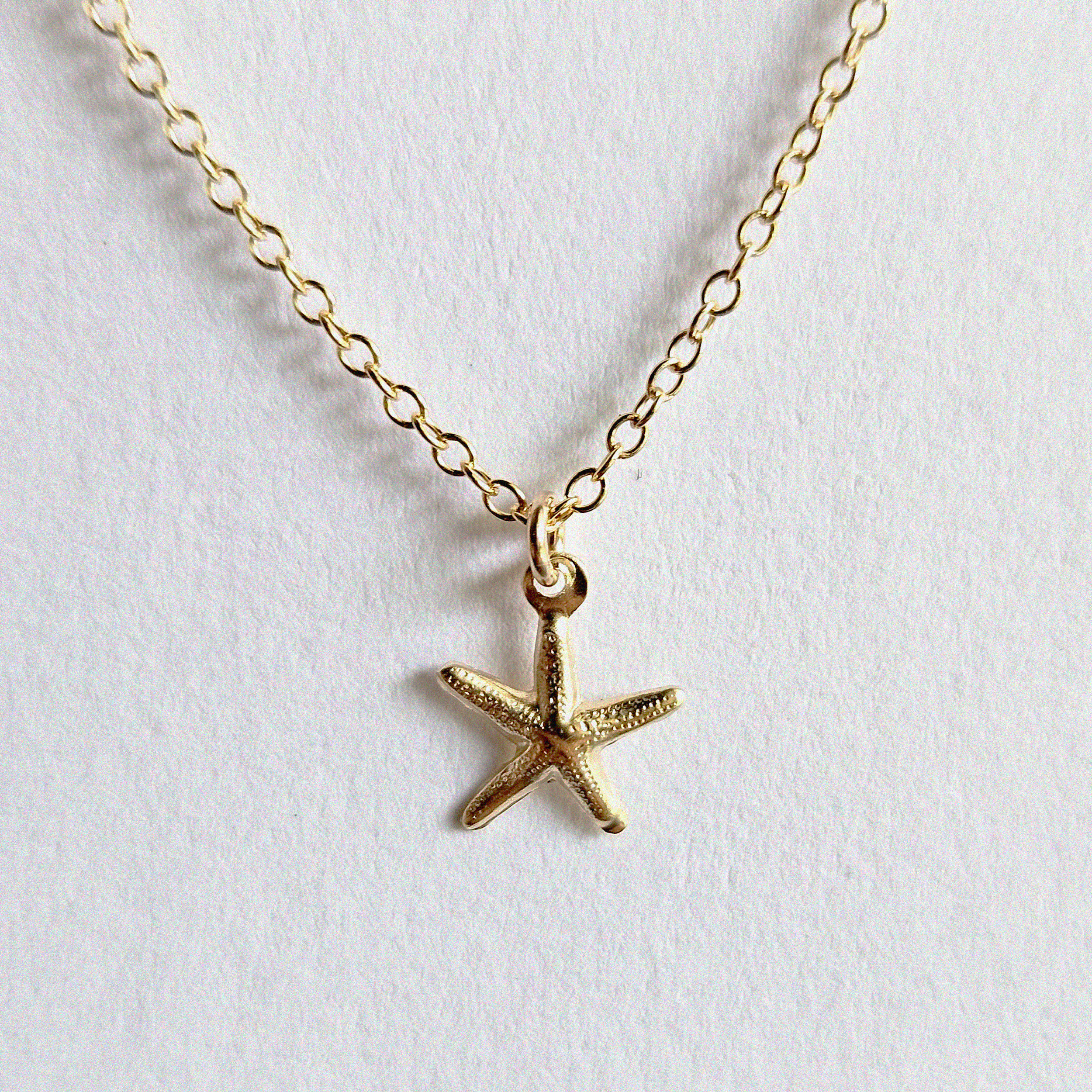 Close-up of starfish charm and pearls with polished finish