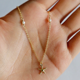 Close-up of starfish charm and pearls on hands