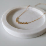 Close-up of textured gold discs evenly spaced along fine chain
