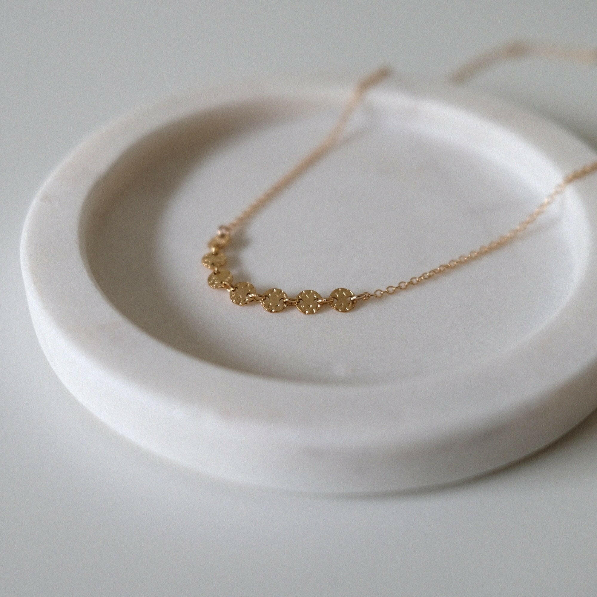 Close-up of textured gold discs evenly spaced along fine chain