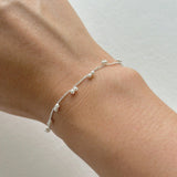 Petite pearl bracelet featuring a pair of lustrous small pearls artfully entwined for elegant style