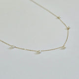 Side angle showing necklace curve and pearl profile against the chain