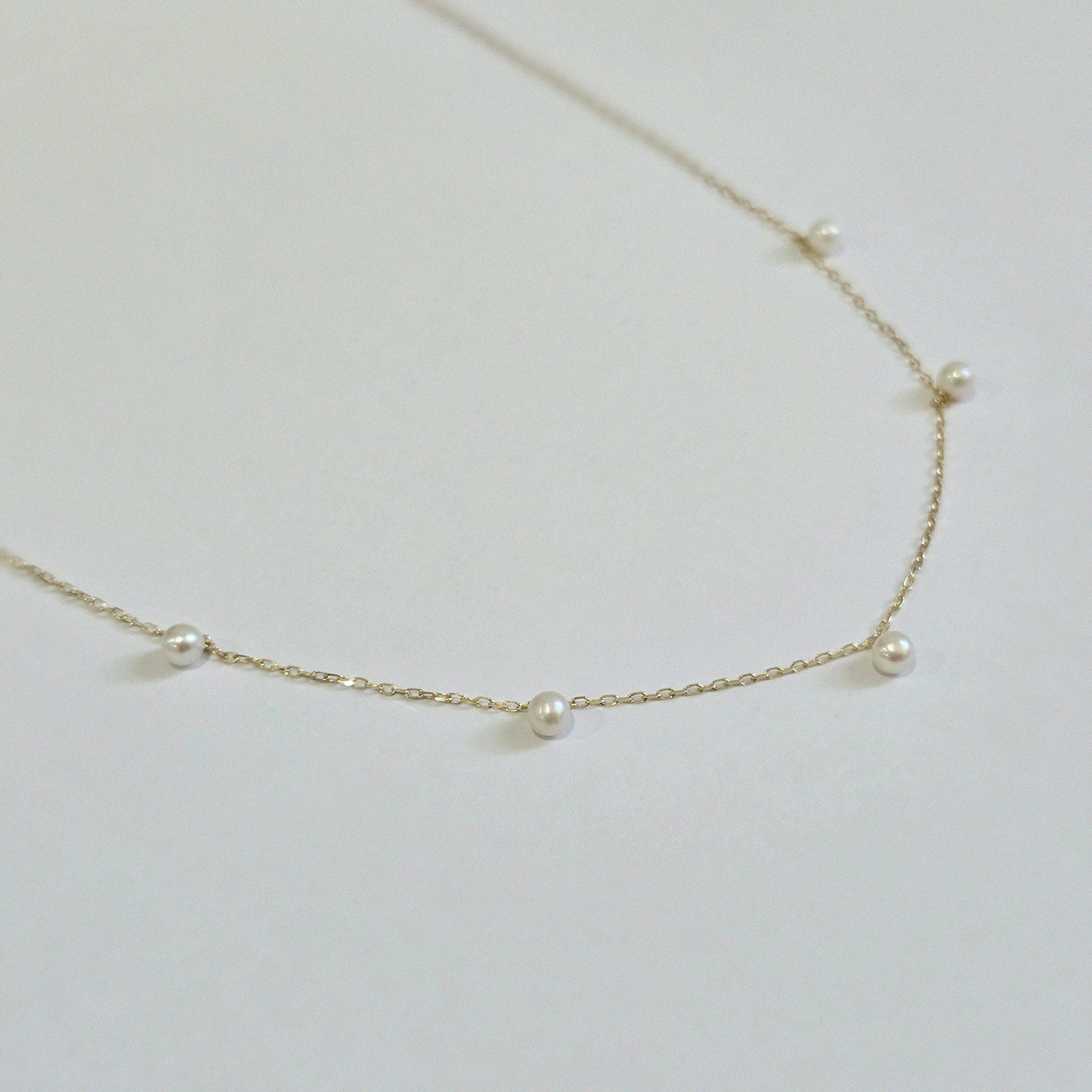 Side angle showing necklace curve and pearl profile against the chain