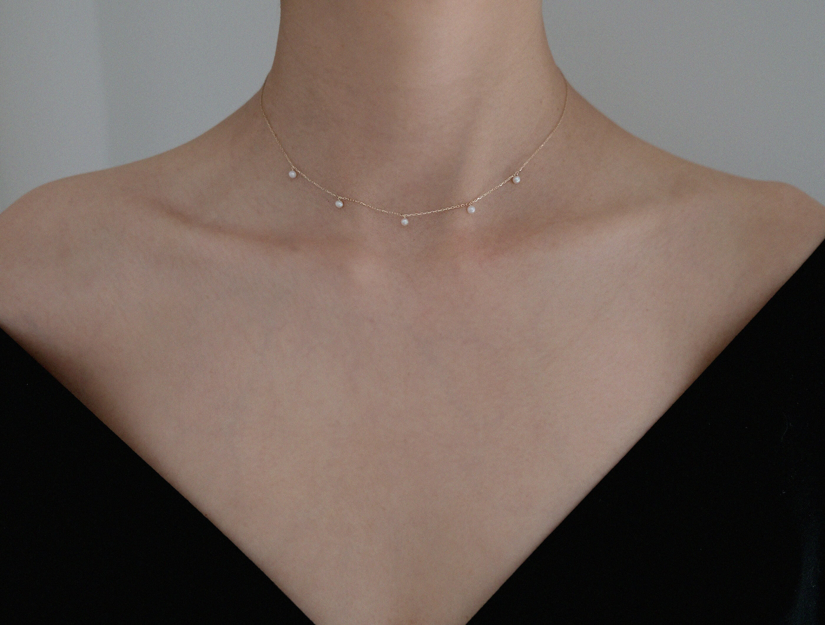 Necklace styled with a black off-shoulder top for an elegant, understated look
