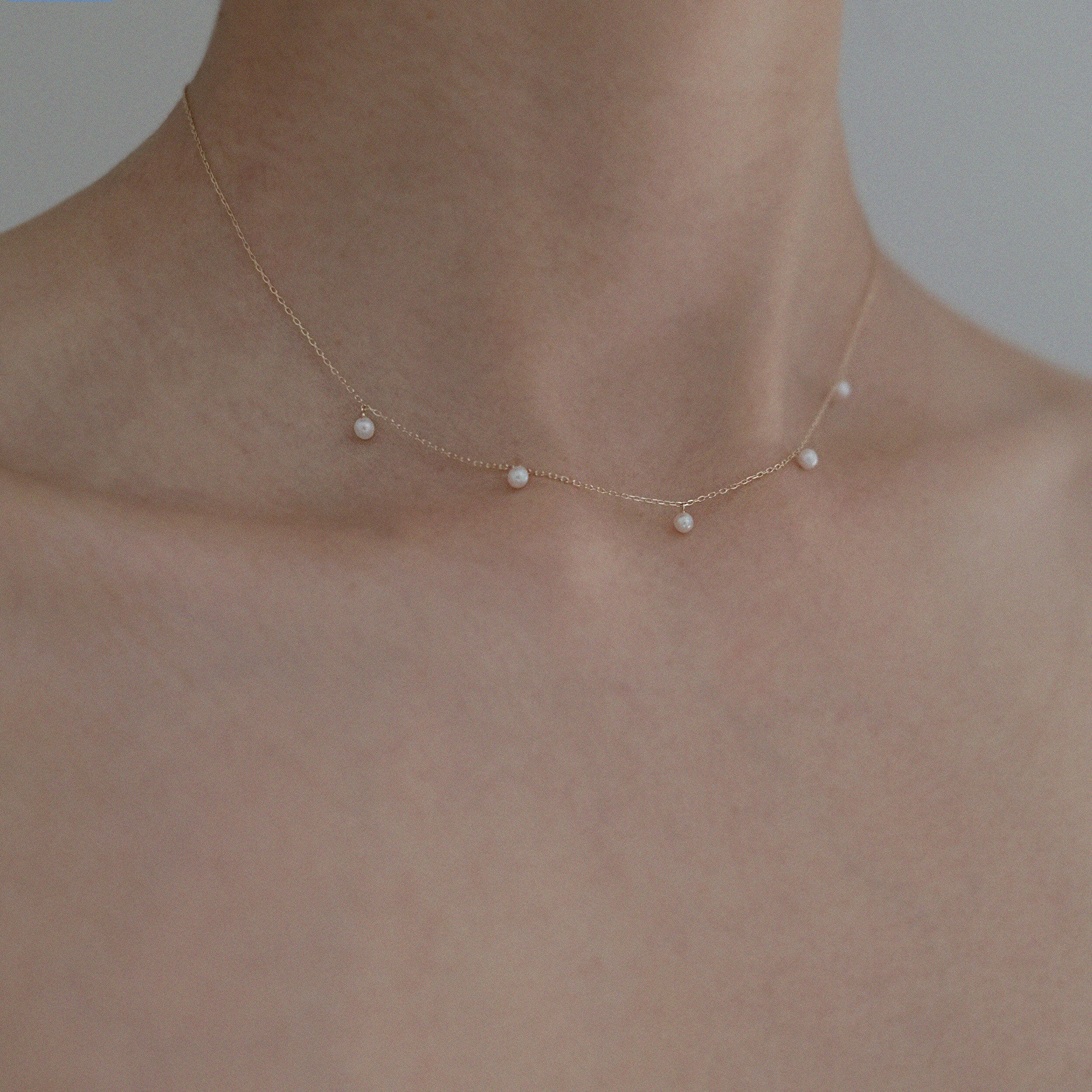 Side shot of model wearing Ariel Perla Necklace, pearls sitting gracefully at collarbone