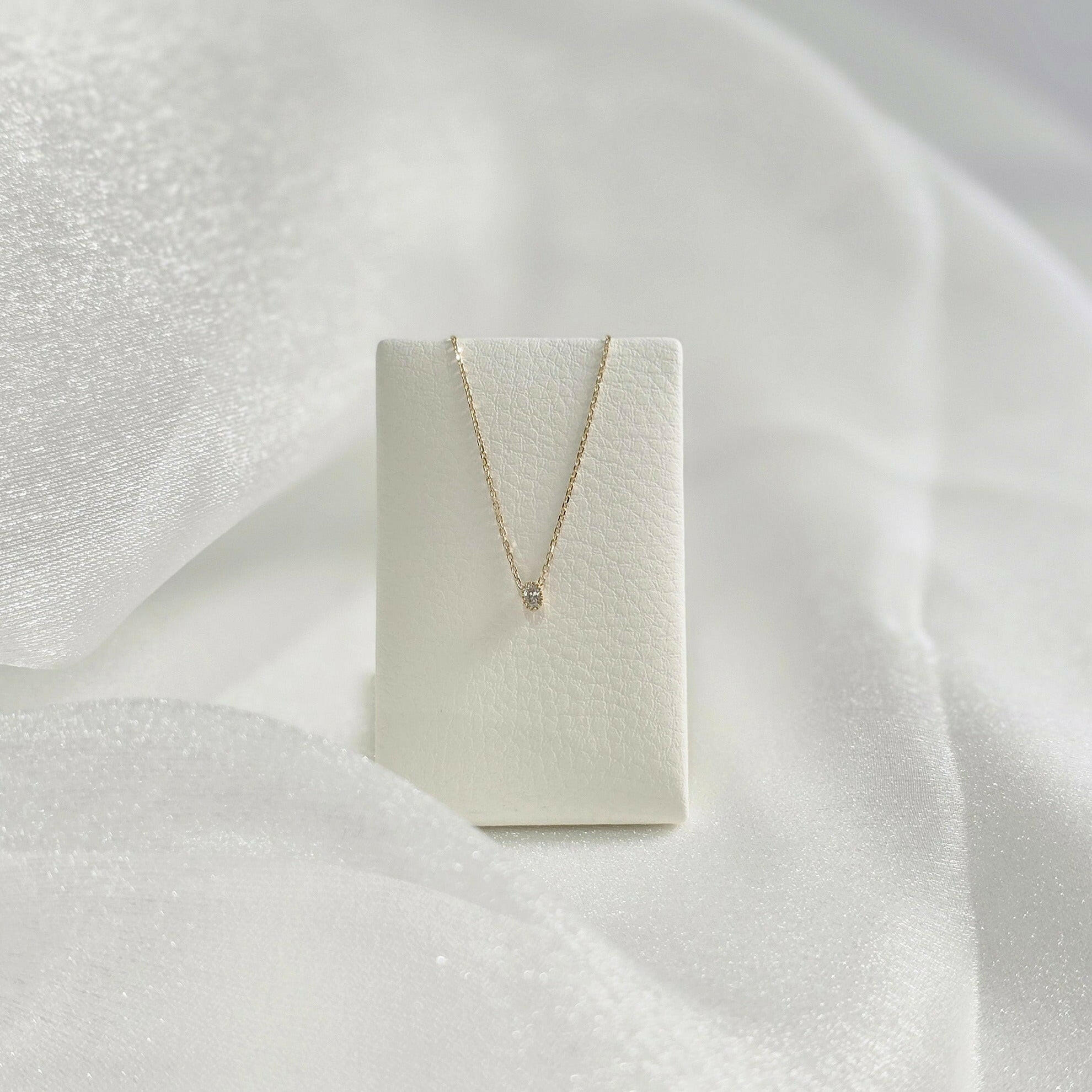Necklace displayed on white velvet holder – pendant centered in graceful drape