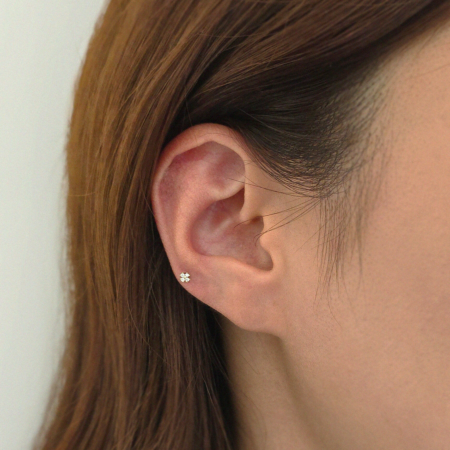 Angled ear close-up featuring delicate flower design in solid gold