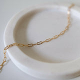 Elongated link bracelet laid out on curved jewelry tray in natural light