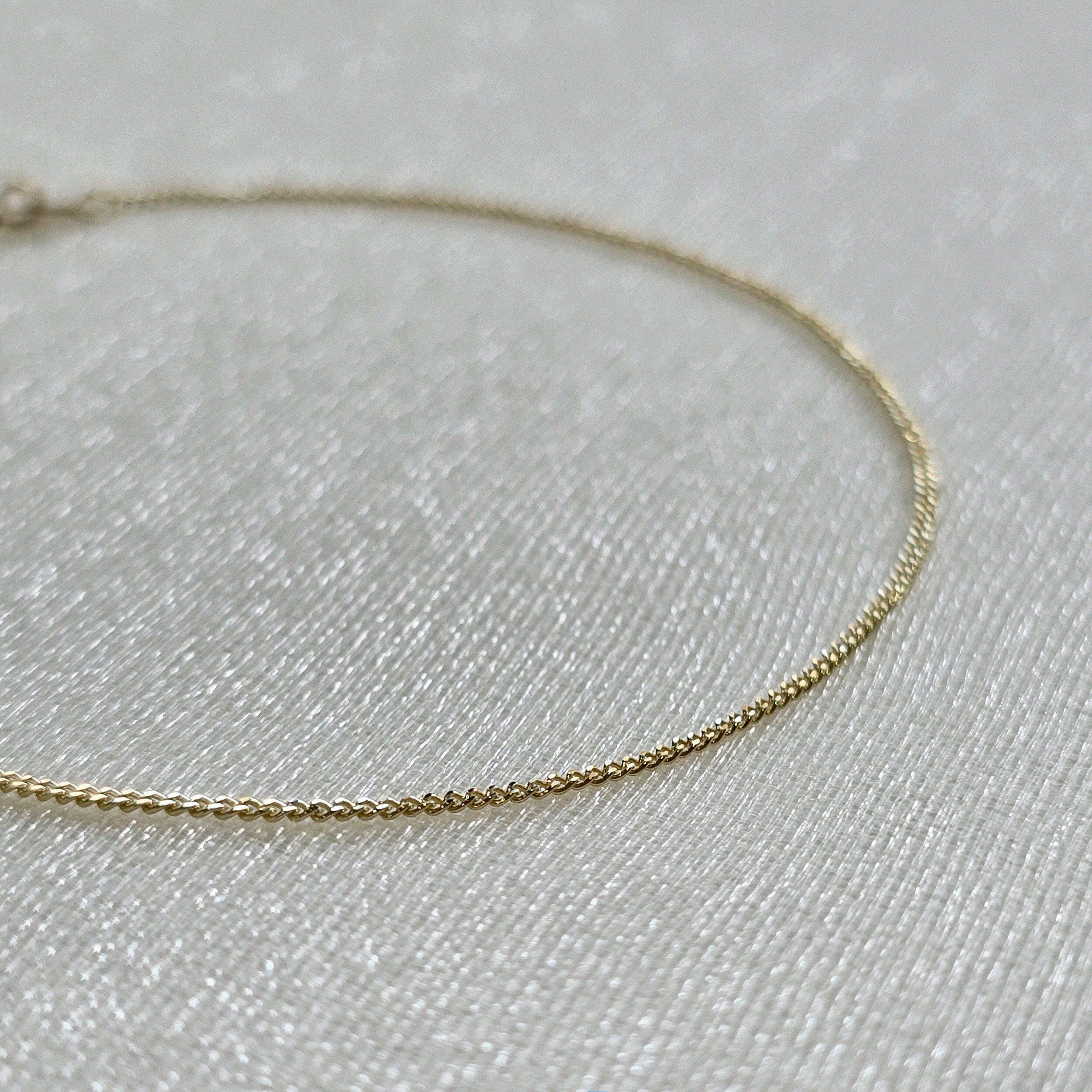Macro view highlighting the sculptural curve of the gold chain