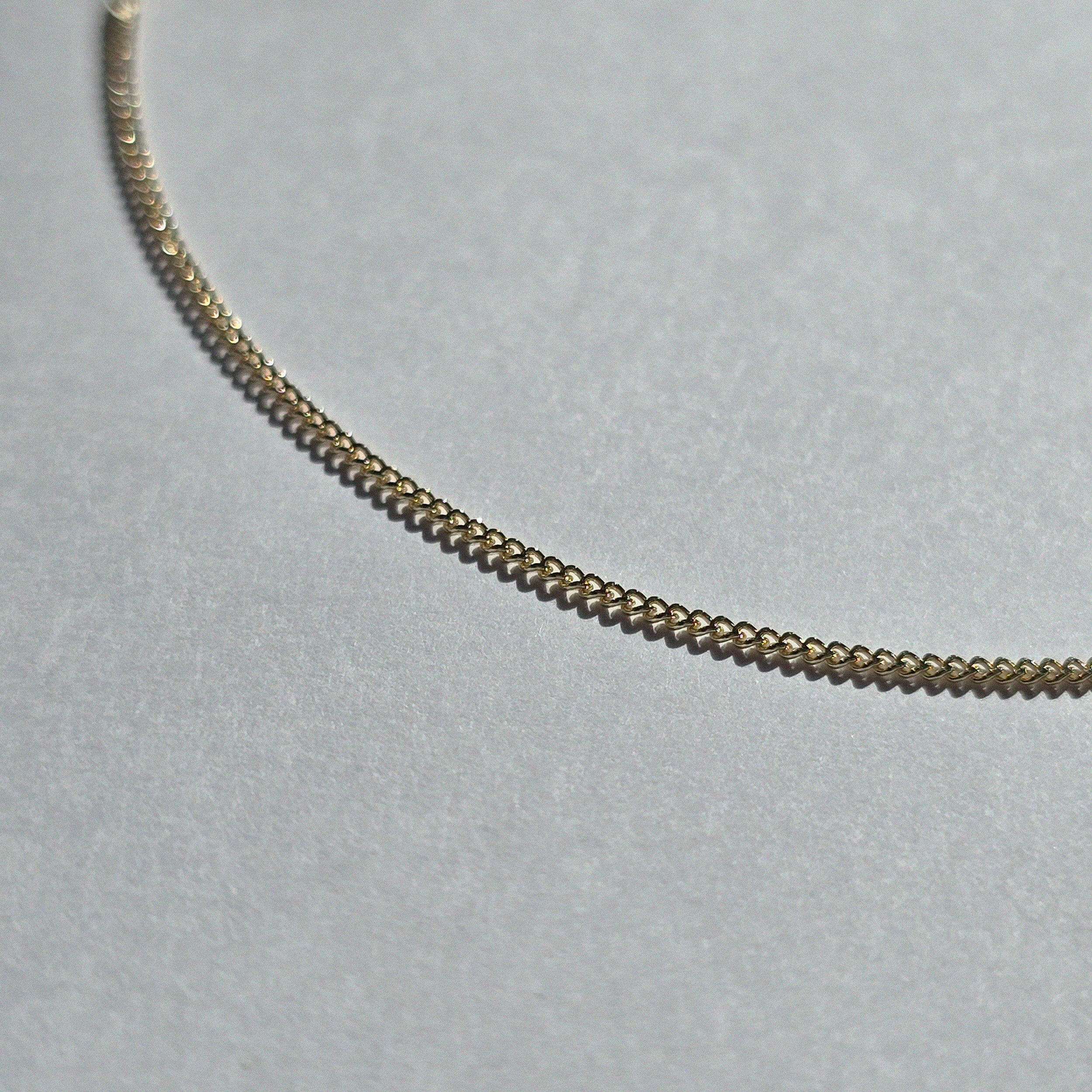 Macro view highlighting the sculptural curve of the gold chain