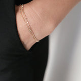 14K Petite Cross Bracelet layered on wrist for a refined look, paired with classic black clothing