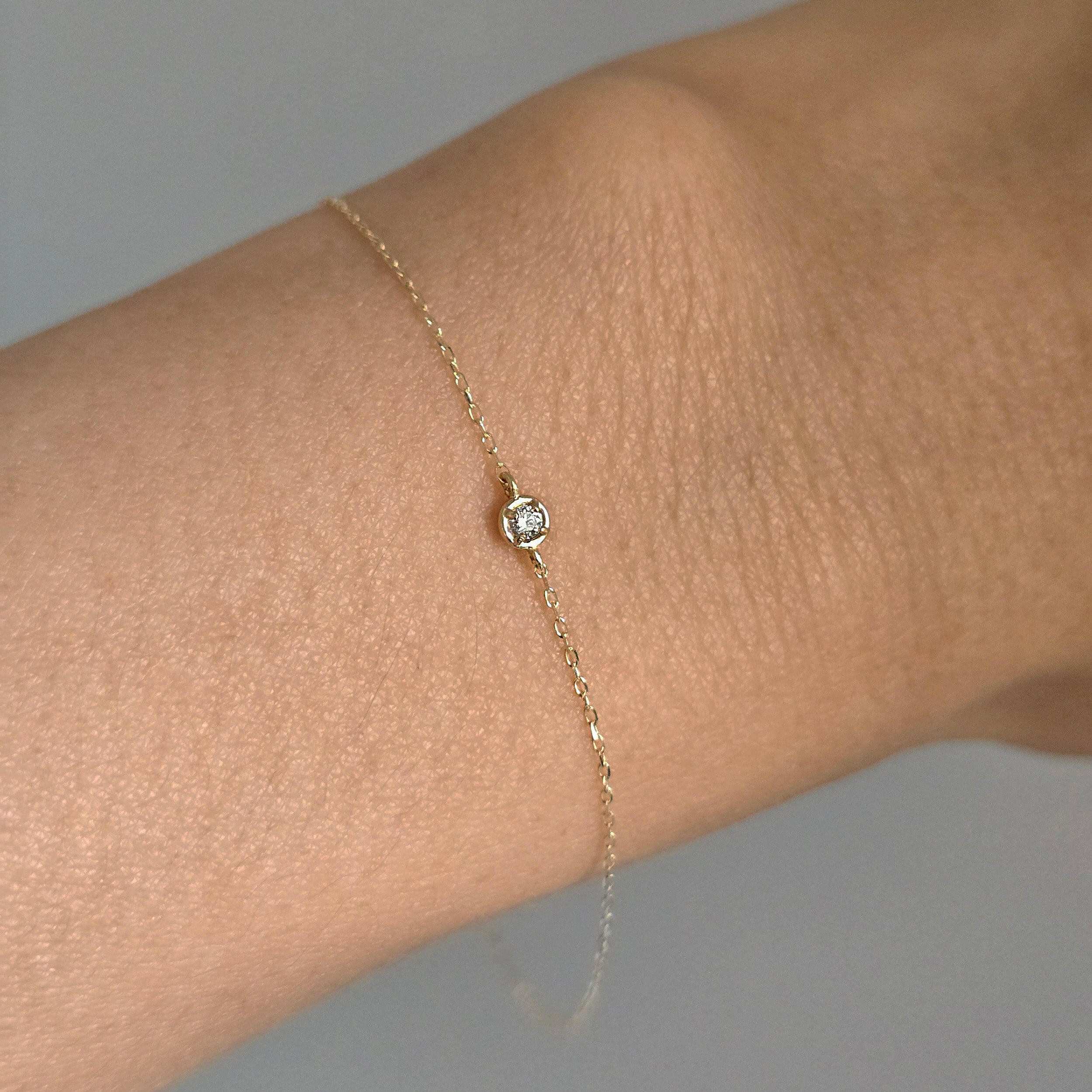 Close-up of dainty gold bracelet with diamond charm styled for daily wear
