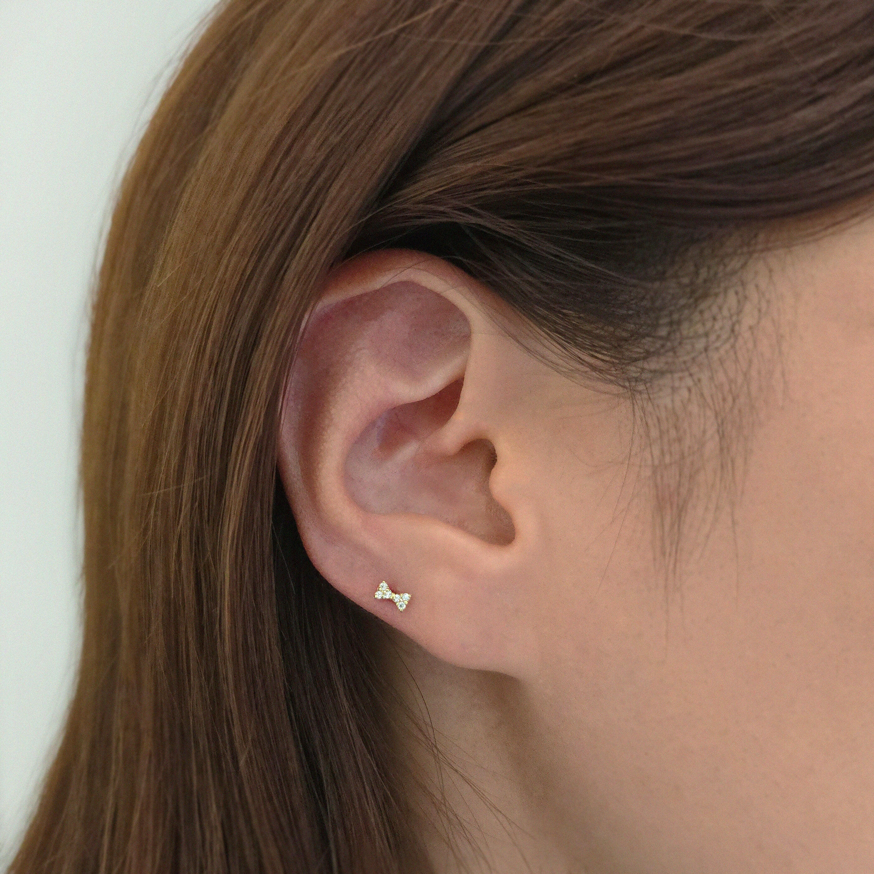 Dainty bow-shaped earring sparkling subtly in side profile