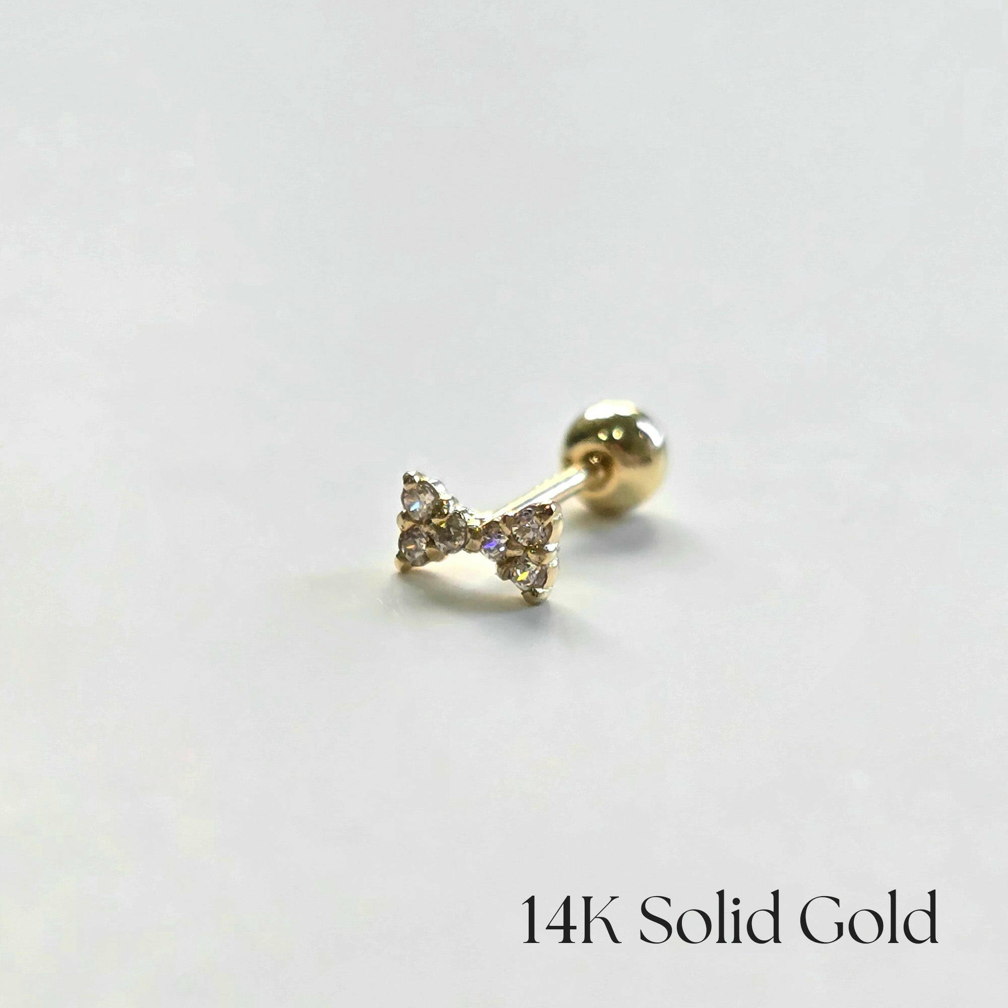 Side view of bow-shaped cartilage earring on white background