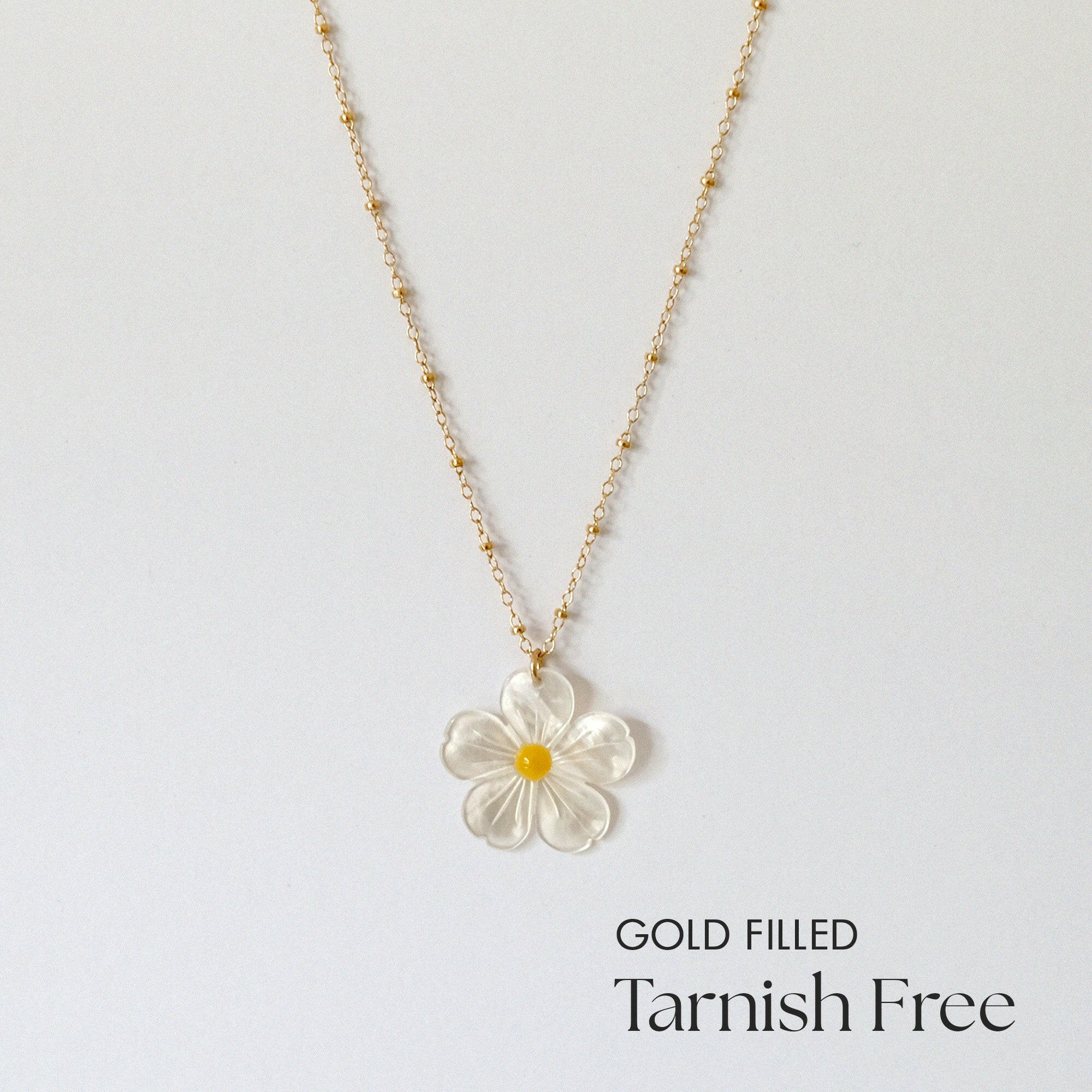 Gold filled daisy necklace with large mother of pearl pendant laid flat