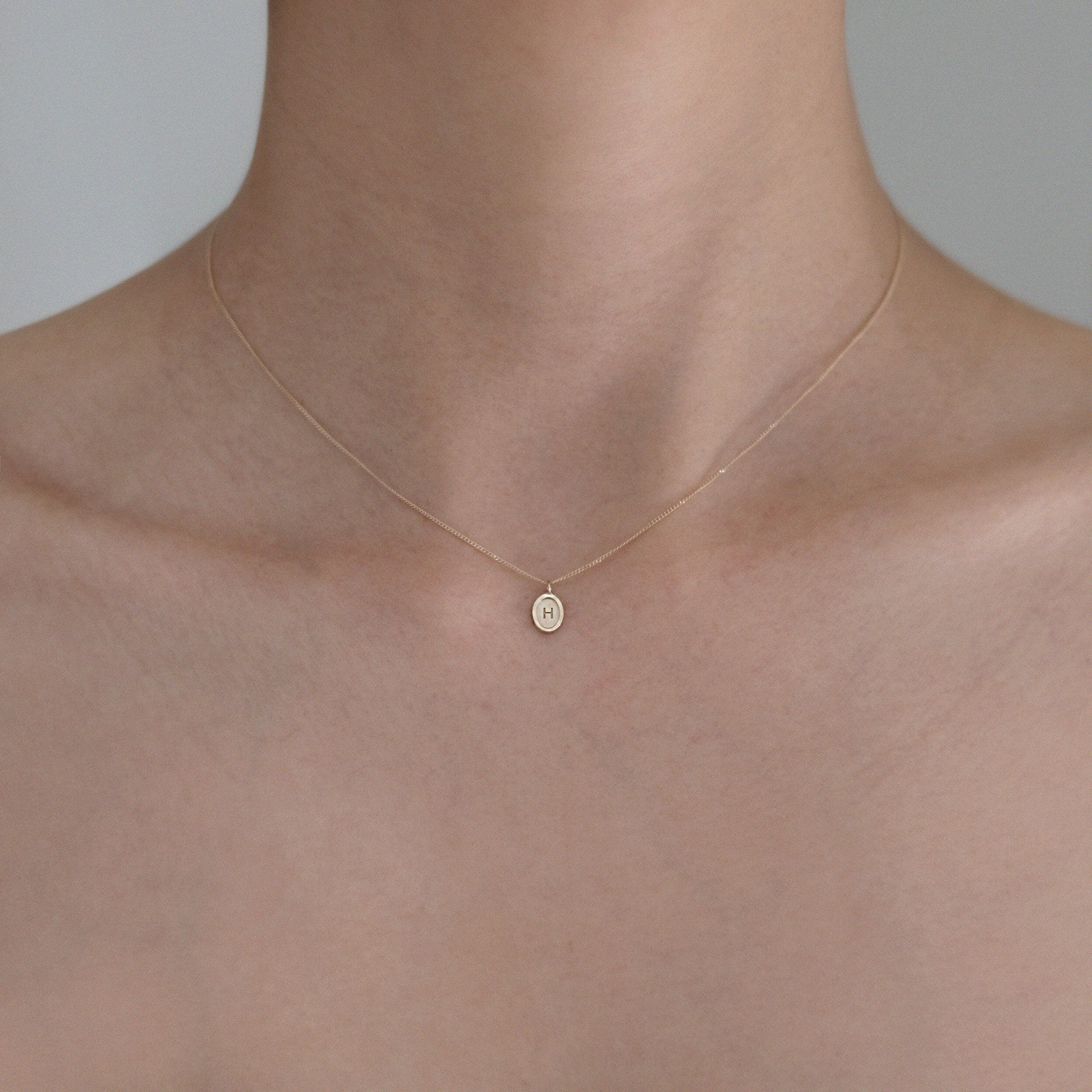 Model wearing Laondrim Dear Initial Necklace – delicate oval pendant in 14K gold