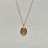 Close-up of the engraved oval initial pendant in solid 14K gold