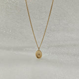 Extreme close-up of 14K solid gold Dear Initial oval pendant engraved with custom letter – high polish finish and delicate texture