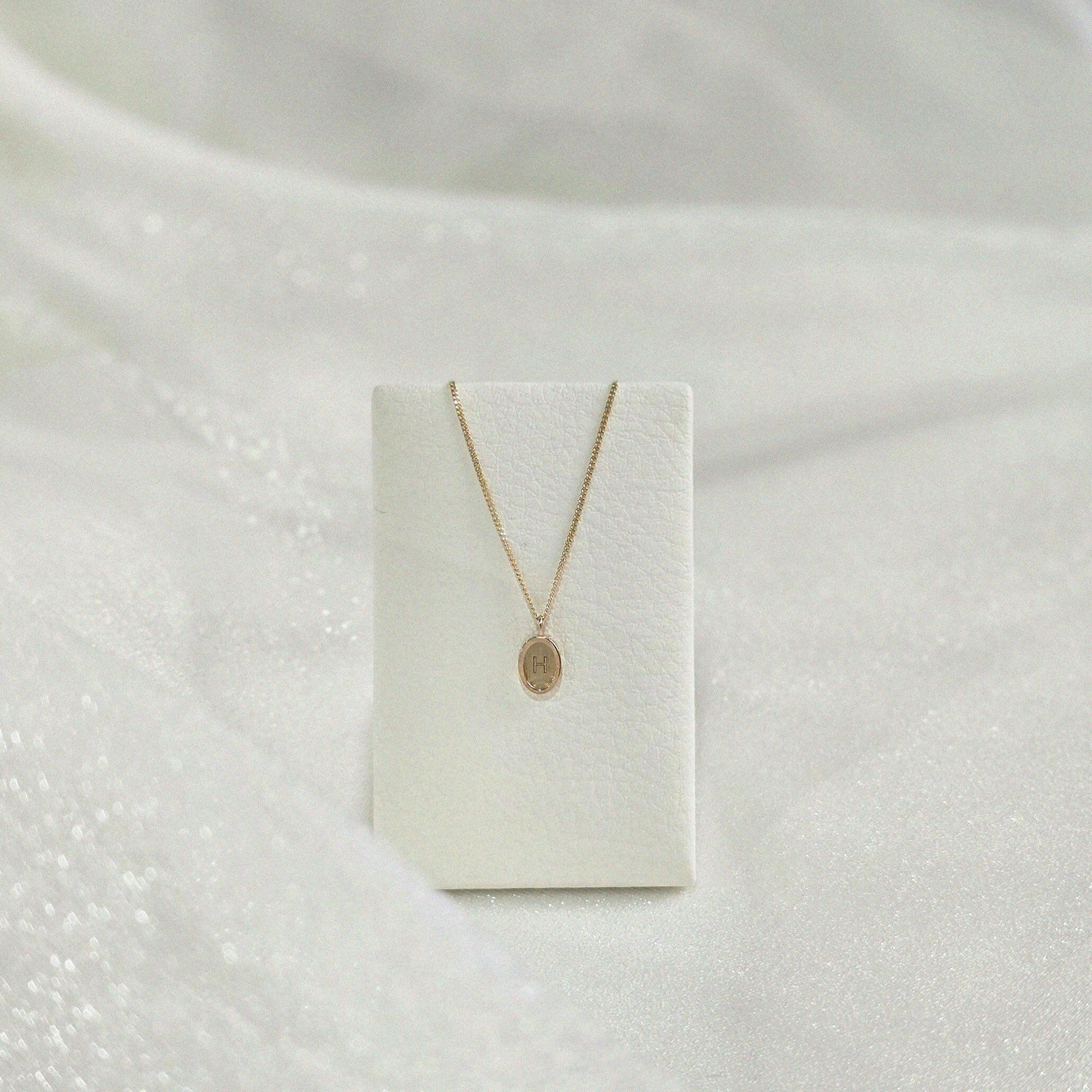 Dear Initial Necklace draped over a necklace holder for display