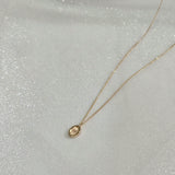 Side angle of oval initial pendant showing curvature and thickness – suspended on a dainty 14K gold chain