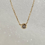 Overhead view of single round diamond set in a minimal 14K gold bezel pendant
