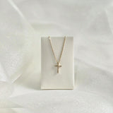 Diamond cross necklace on soft cream leather necklace stand, pendant in focus
