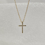 Close-up of 14K solid gold cross pendant with multiple set diamonds