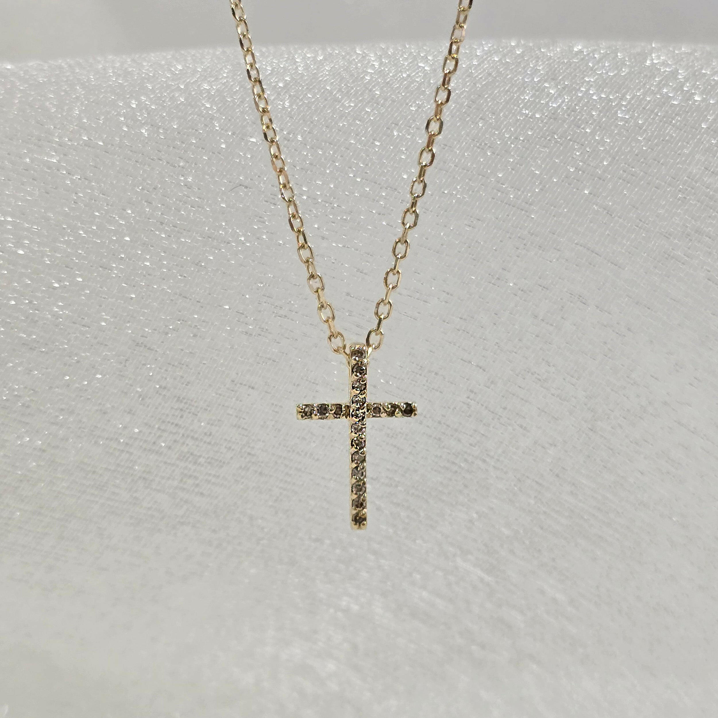 Close-up of 14K solid gold cross pendant with multiple set diamonds