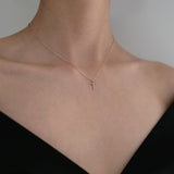 Model wearing Diamond Croce Necklace with cross pendant resting against skin, styled with off-shoulder black top