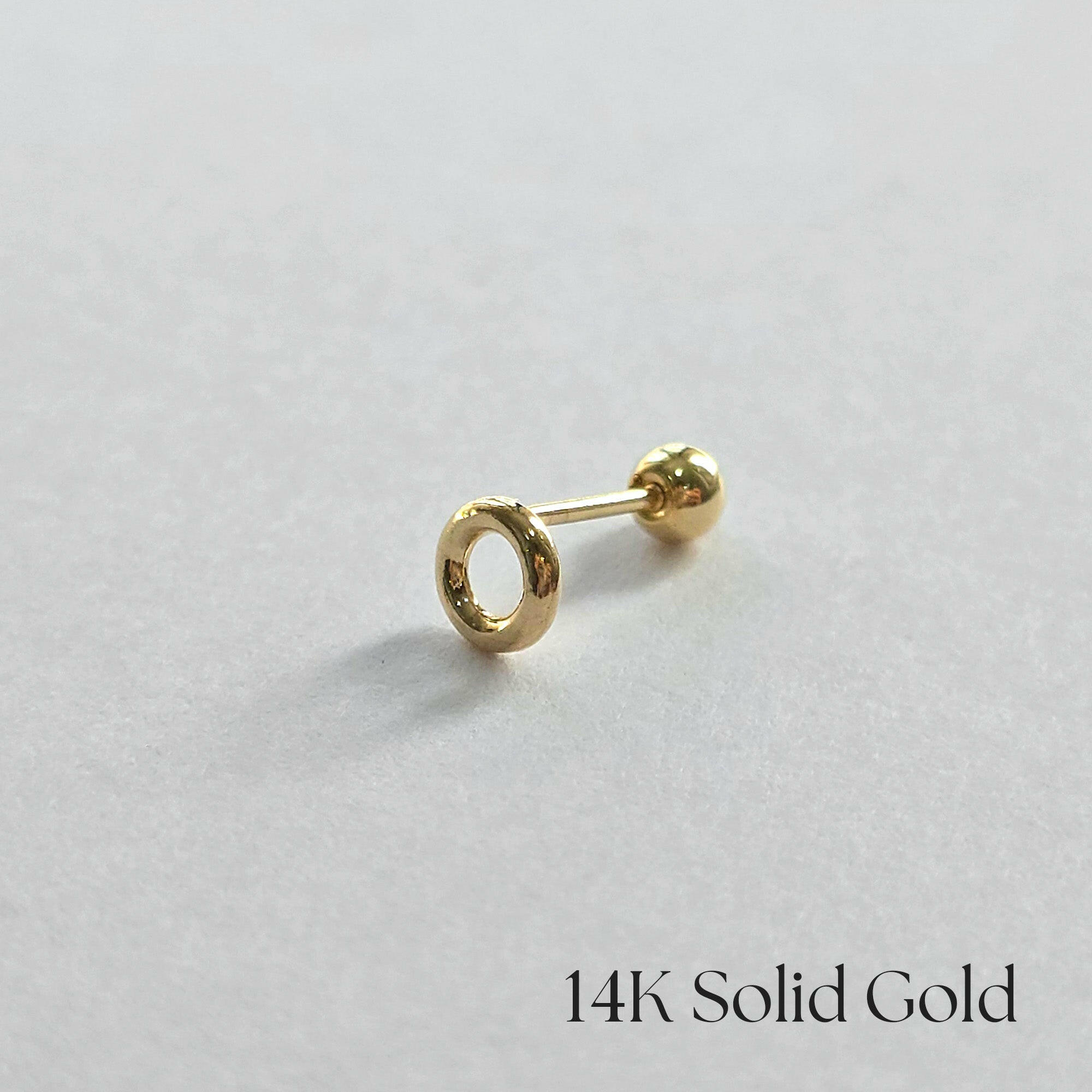 Side view of 14K gold donut cartilage earring on white background