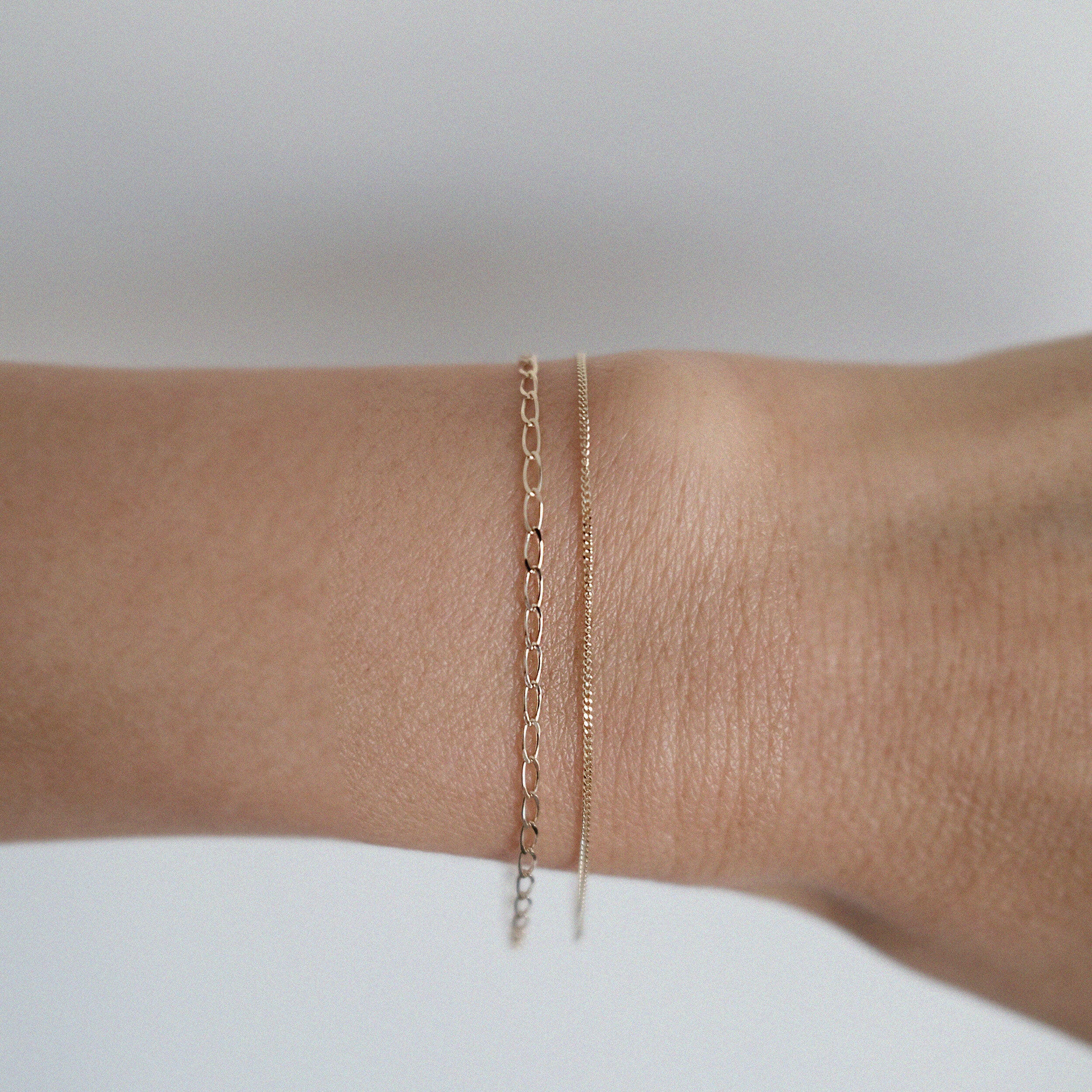 Capri Bracelet in solid gold worn on wrist with Bold link chain bracelet