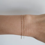 Model wearing the Elba Bracelet alongside fine gold chains for an elegant layered effect